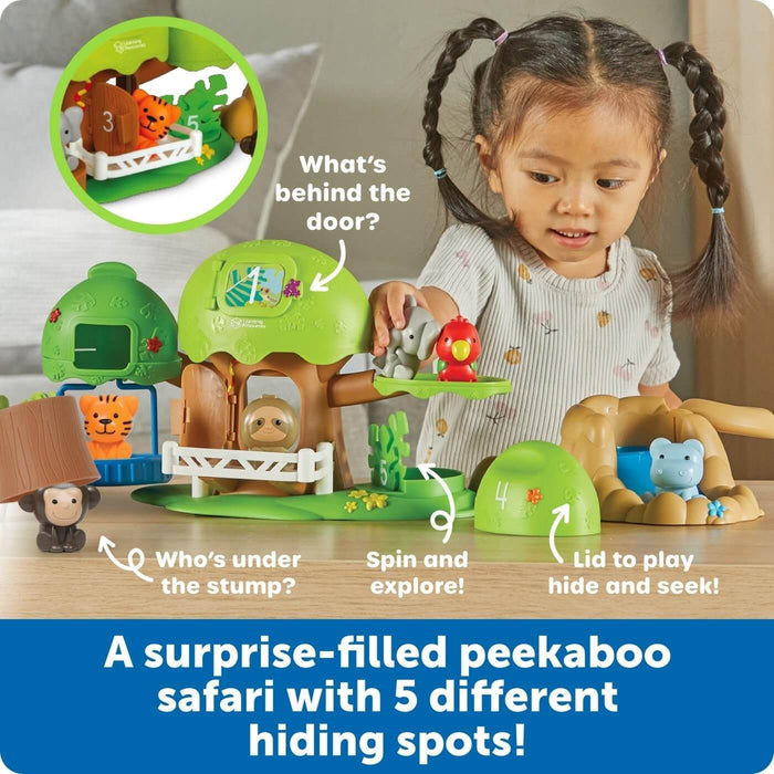 Toddler playing with a green safari playset featuring plastic animals and five numbered peekaboo hiding spots.