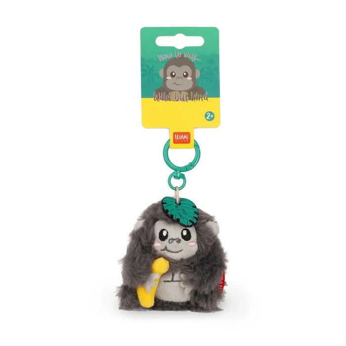Grey plush gorilla keychain holding a yellow banana, with a green clip and leaf, on teal and yellow retail packaging.