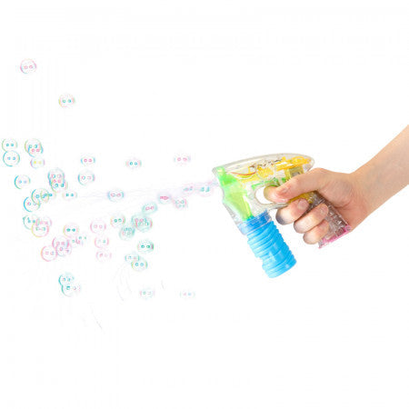 Hand holding a clear plastic bubble gun with blue and yellow accents shooting a stream of colorful bubbles.
