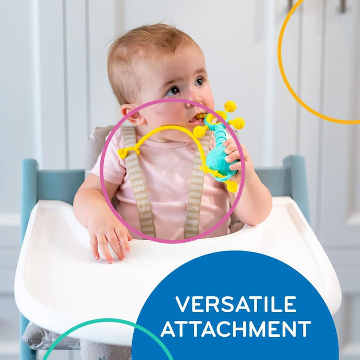 Baby in a high chair holding a blue teether toy attached to their harness by a yellow silicone Liinklz tether.