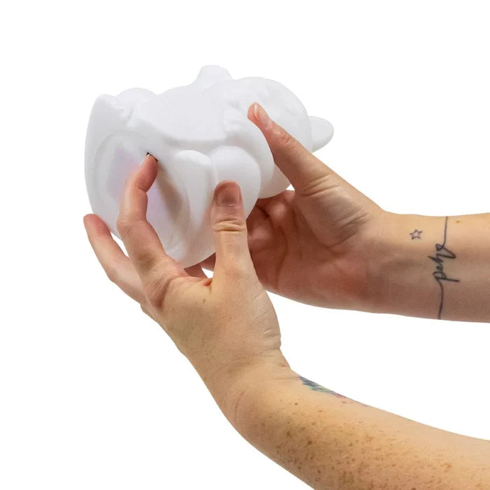 Hands squeezing a soft, white silicone cat-shaped light to demonstrate its squishy texture.