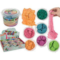 Colorful Magic Clay Sand in tubs and piles with a hand stretching a pink strand of the sand against a white background.