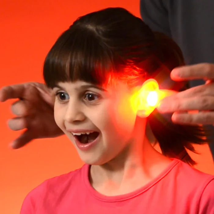 Surprised young girl with a bright glowing red light effect appearing to be pulled from her ear by hands.