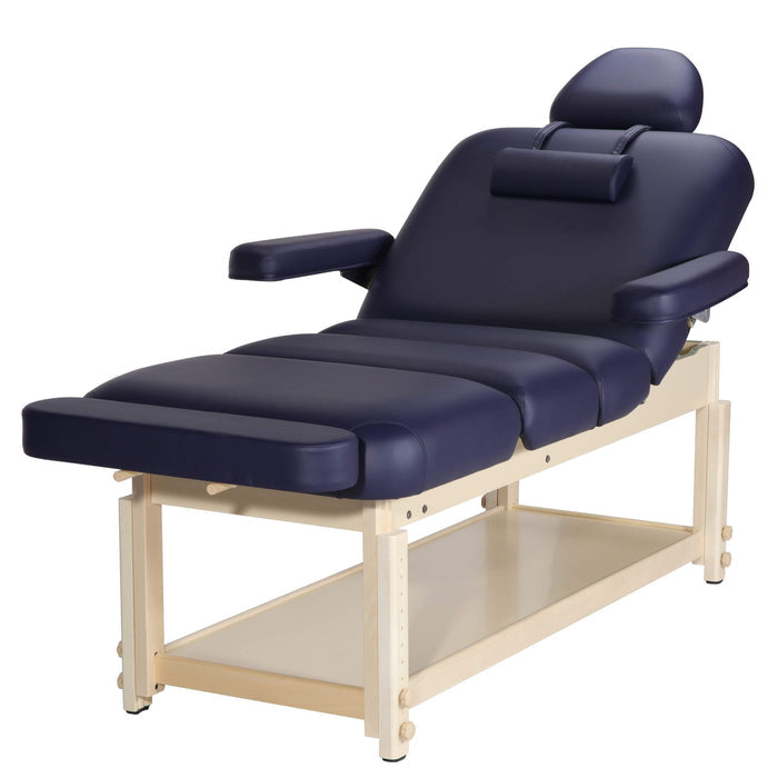 An angled view focusing on a navy blue detachable footrest extension pad mounted securely onto a stationary wooden spa treatment table via universal twin insertion dowels; highlights the thick, high-density small-cell foam padding layer and fluid-resistant upholstery finish, allowing chiropractors and sports massage clinics in Birmingham to optimize existing equipment for maximum patient leg support.