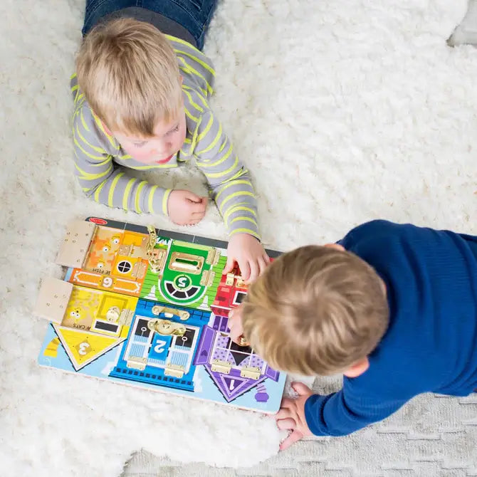 Two children on a white rug play with a colorful activity board featuring metal latches and six numbered doors.