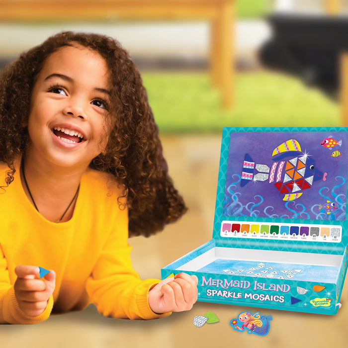 Smiling child crafting a colorful fish mosaic with a Mermaid Island Sparkle Mosaics kit and bright stickers.