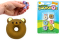 Hand squeezing a purple animal squishy next to a brown bear donut and a pack of 6 colorful animal-faced donut squishies.