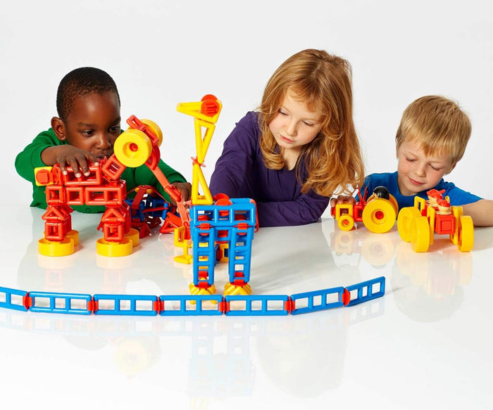 Three kids building a crane, tractor, and figures using red, blue, and yellow Mobilo construction blocks and wheels.