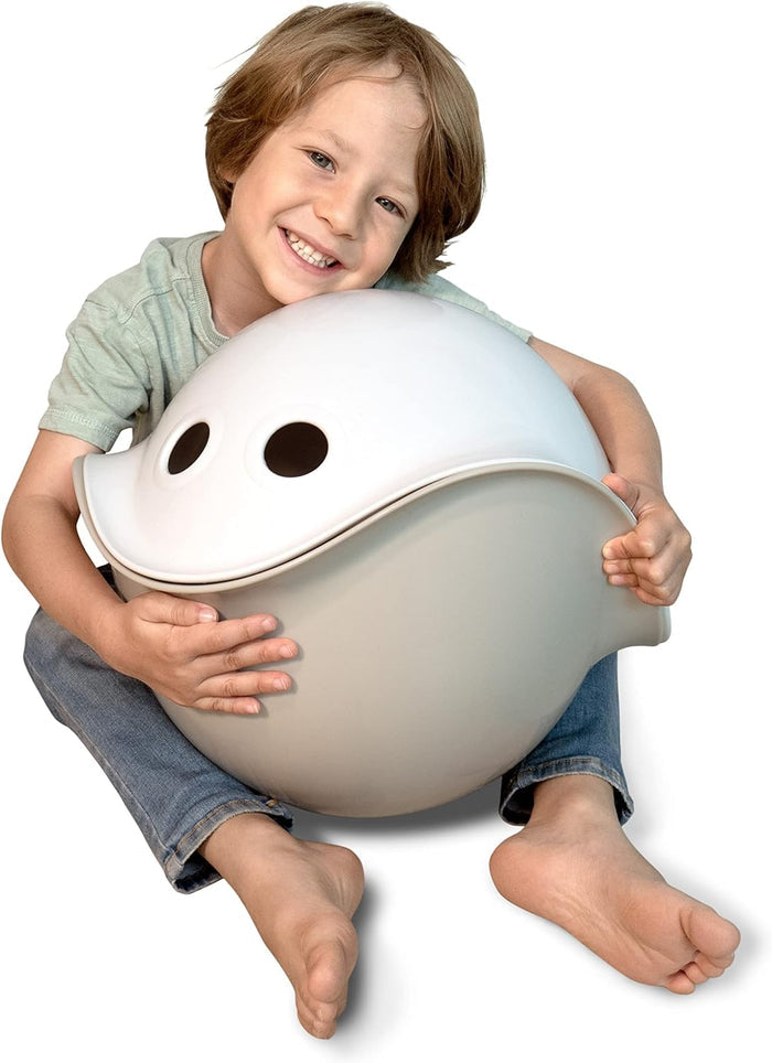 Child hugging two dome-shaped toy shells, one white with eye holes and one light grey.