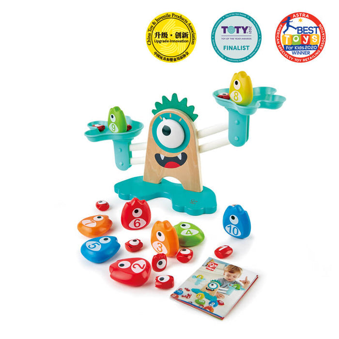 Wooden monster balance scale with turquoise arms, colorful numbered monster weights, and three award seals.