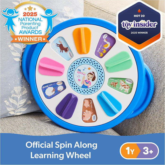 Blue circular toy wheel with colorful handles, farm animal drawings, and a cartoon of Ms. Rachel in the center.