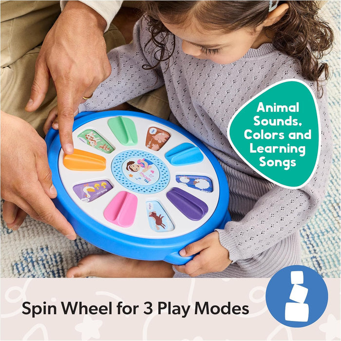 Child and adult play with a round blue toy featuring colorful animal buttons and Ms. Rachel’s face in the center.