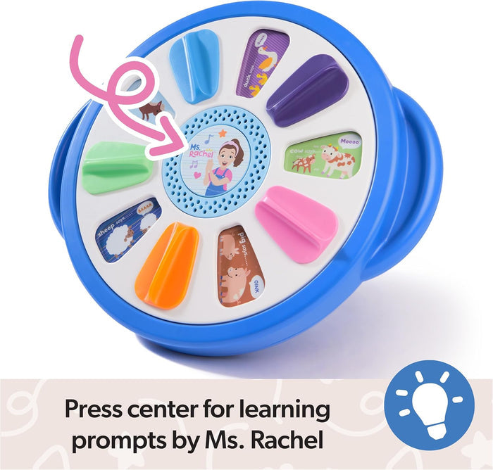 Circular blue toy with colorful tabs and farm animal art. A pink arrow points to the central Ms. Rachel speaker button.
