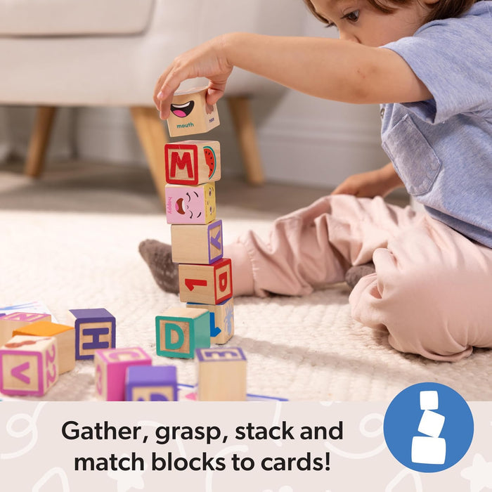 A child stacks colorful wooden blocks featuring letters, numbers, and facial expressions on a cream rug.