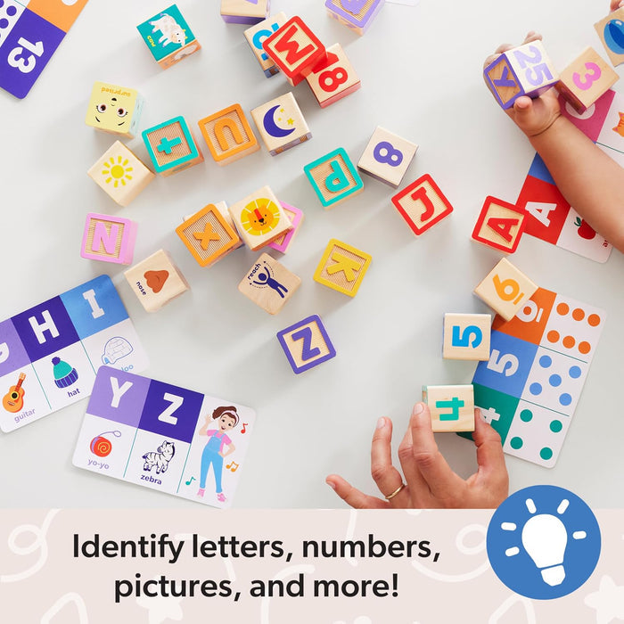 Brightly colored wooden blocks with letters, numbers, and icons scattered near illustrated activity cards.