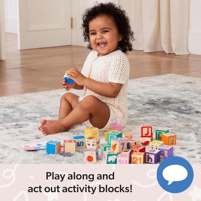 Smiling baby sitting on a rug playing with colorful wooden alphabet and number blocks and activity cards.