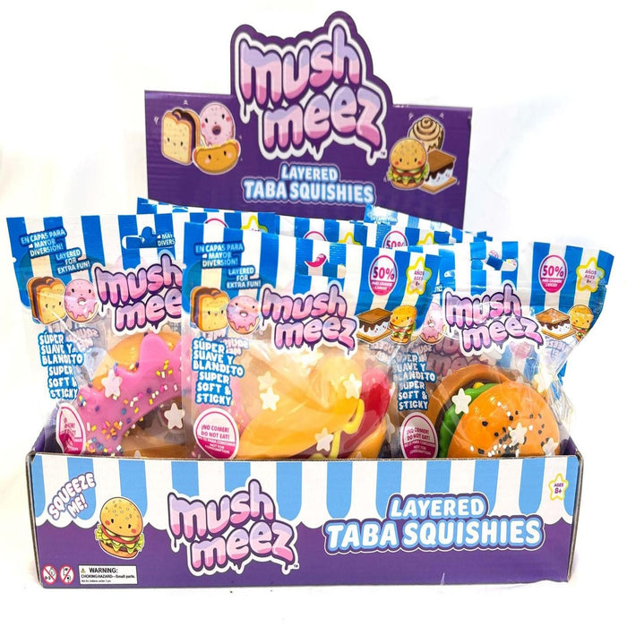 Retail display of food-themed Mush Meez Layered Taba Squishies in colorful blue and white striped packaging.