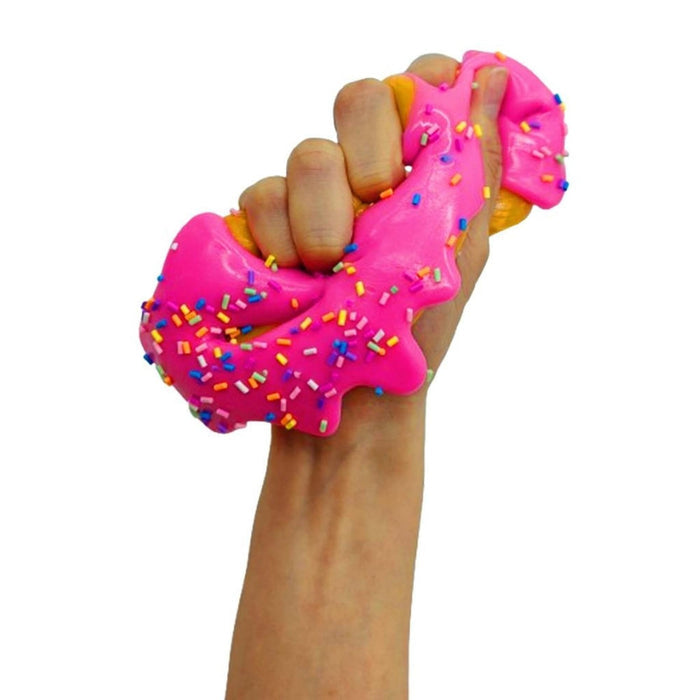 Hand squeezing a bright pink donut squishy toy with colorful sprinkles, showing its soft and stretchy texture.