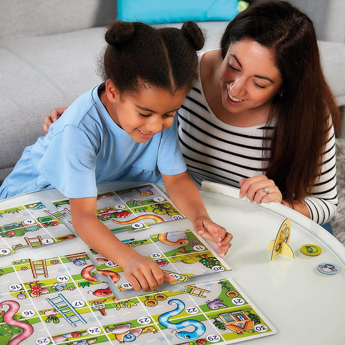 Child and adult play a colorful snakes and ladders board game with large, numbered puzzle-piece tiles.