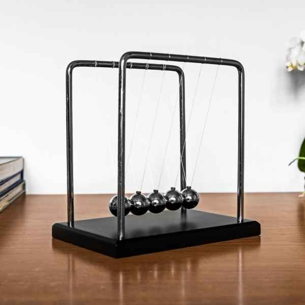 Five chrome spheres hanging by thin strings from a silver metal frame on a black rectangular base.