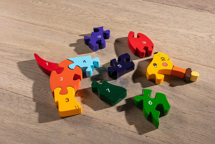 Colorful numbered wooden jigsaw pieces 1-10 scattered on a wood surface, partially assembled to form a dog.