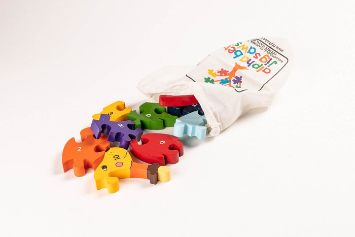 Colorful numbered wooden dog puzzle pieces spilling out of a white canvas drawstring bag.