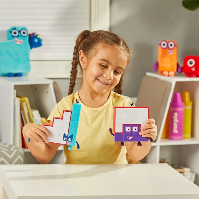 Smiling girl holds a blue and white stepped block toy and a purple and white square block character.