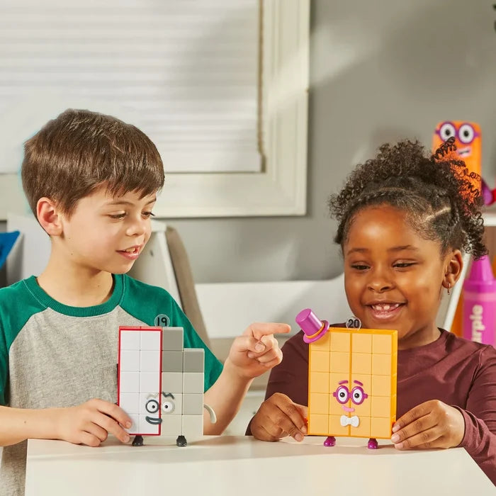Two kids hold block figures: one grey and white with red trim, one orange with a purple top hat and pink glasses.