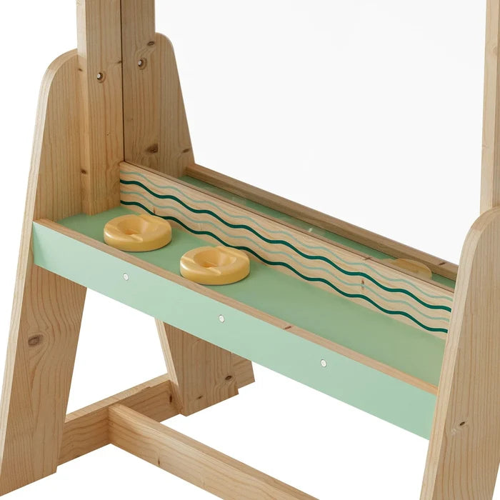 Light wood easel detail showing a mint green tray with wavy lines, two yellow holders, and a built-in mirror.