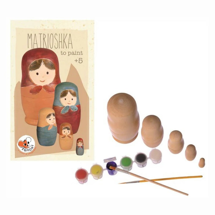 Packaging next to five unpainted wooden nesting dolls, six small paint pots, and two fine-tip paintbrushes.