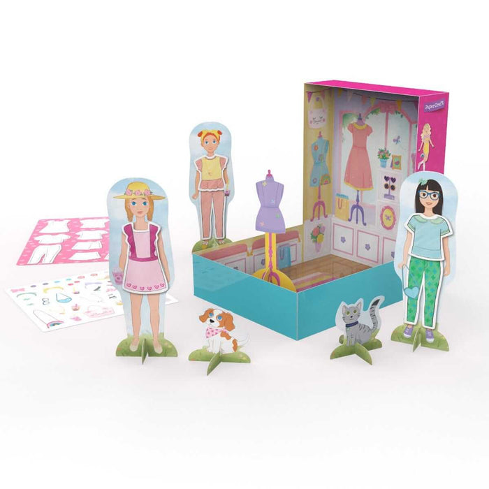 Cardboard boutique play set with three paper doll figures, pet cutouts, and a foldable pink and teal shop scene.