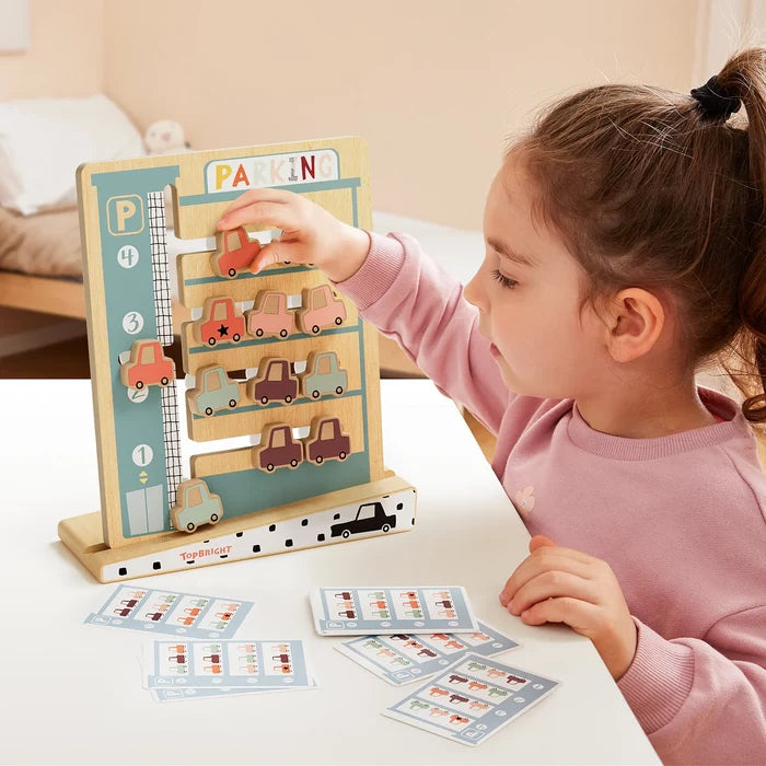 Child plays with a wooden parking logic puzzle, sliding colorful car pieces into slots on a vertical board.