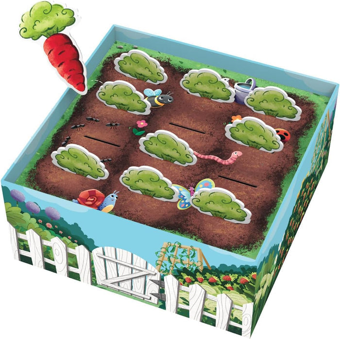 Garden-themed game box with slots for green bushes, garden insects, and a large red carrot being inserted.