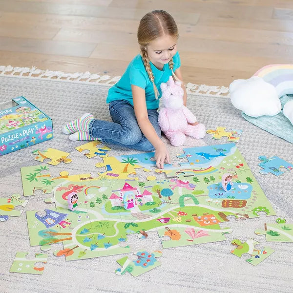 Young girl building a colorful fantasy floor puzzle with a pink castle, rainbow, and 3D stand-up character figures.
