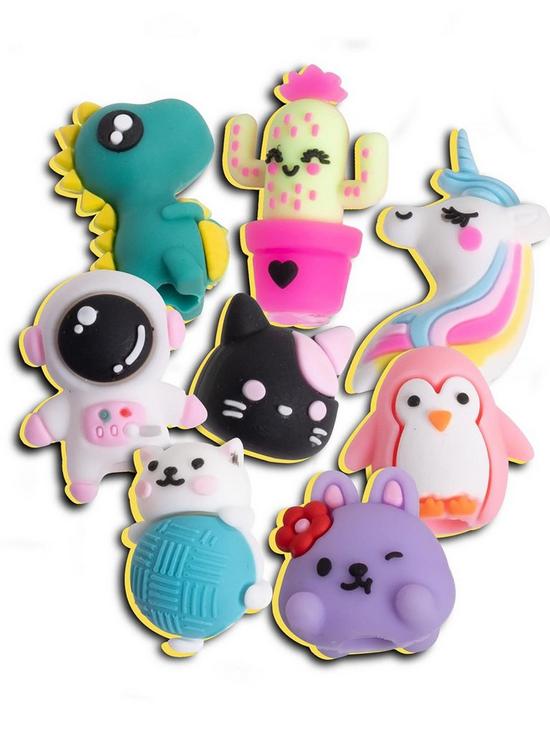 Eight colorful silicone charms: teal dinosaur, cactus, unicorn, astronaut, cat, penguin, and bunny character toppers.