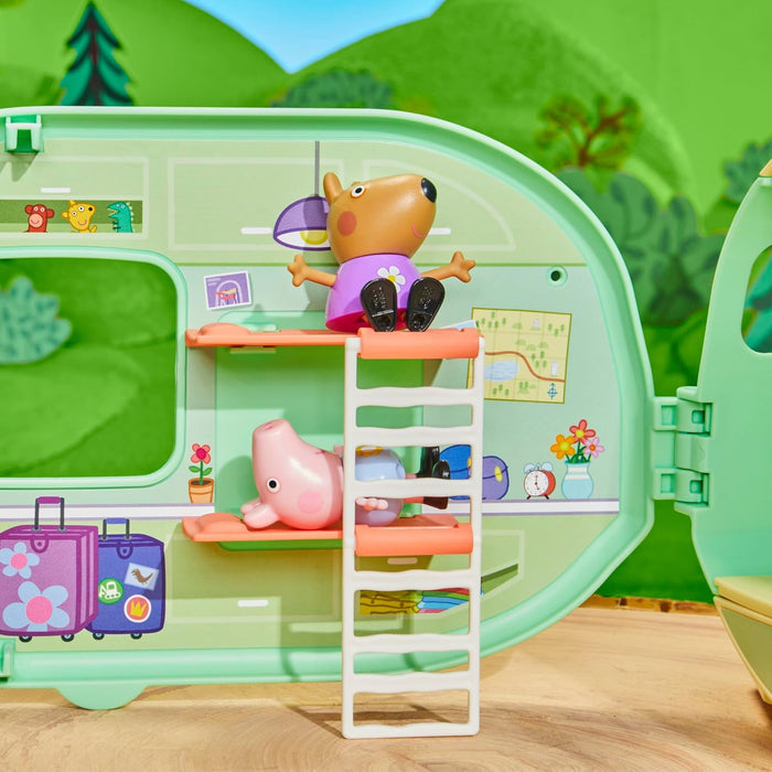 Interior of a green toy caravan with Peppa Pig and a dog figure on orange bunk beds and a white ladder.
