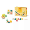 Pastel wooden toys including a turtle, shape puzzle, and lacing fish with a yellow product box labeled 18m.