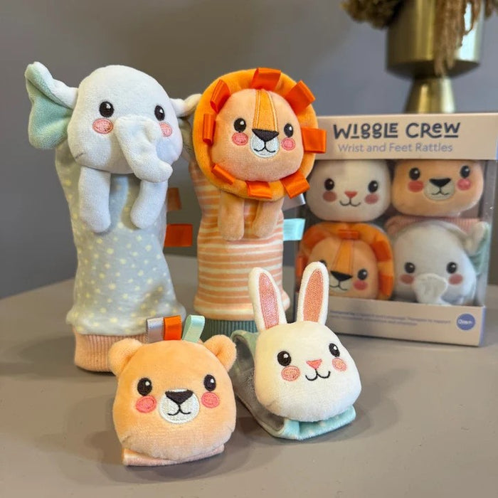 Plush animal-themed wrist and feet rattles featuring an elephant, lion, bear, and rabbit alongside their packaging.