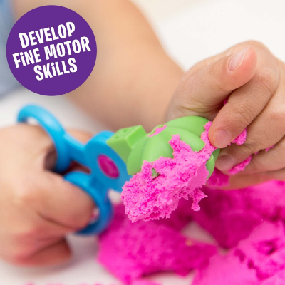 Child using blue and green scissor tools to scoop bright pink sand. Text reads: Develop fine motor skills.