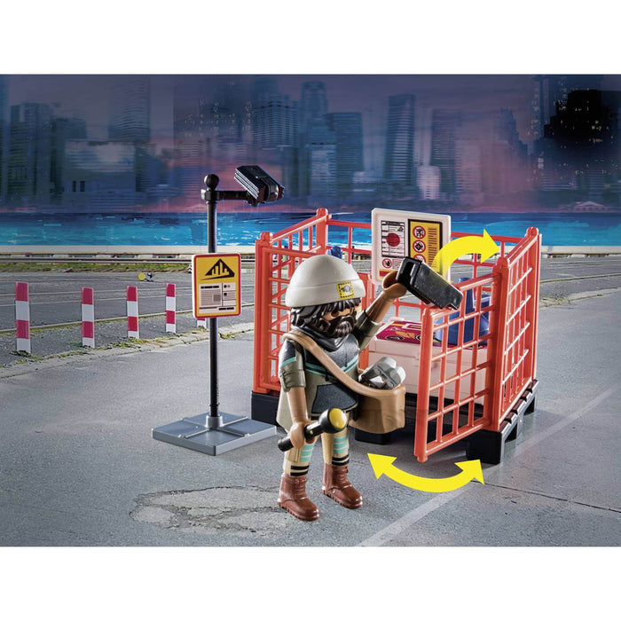 Playmobil figure in a white hat holding a flashlight and radio near an orange cage and surveillance camera.