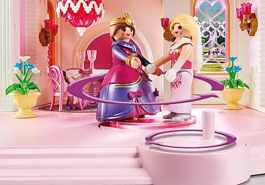 Two Playmobil figures in purple and pink gowns dancing on a spinning platform in a pink toy castle ballroom.