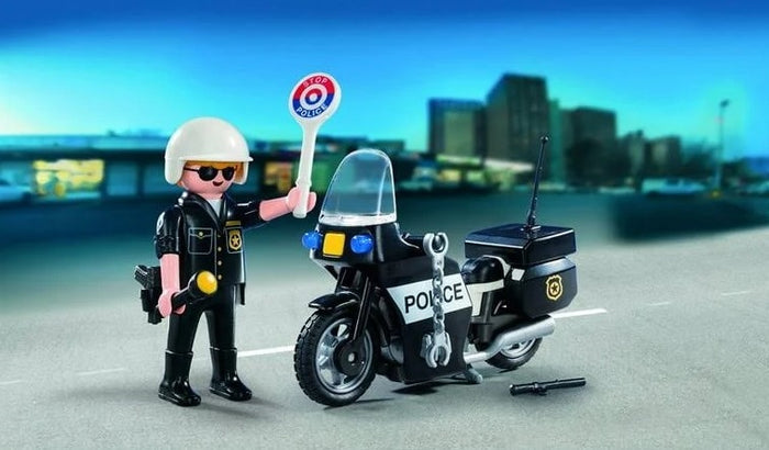 Playmobil police figure in white helmet holds a stop sign next to a black motorcycle with handcuffs and antenna.