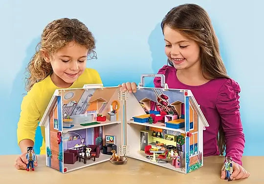 Two girls play with an open white portable dollhouse showing four colorful furnished rooms and small figures.