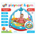 Baby in a colorful farm-themed inflatable ring with a blue overhead toy arch and hanging animal toys on packaging.