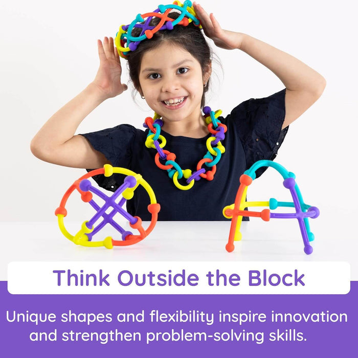 Girl wearing a colorful, flexible toy crown and necklace with interlocking sphere and tripod shapes on a table.