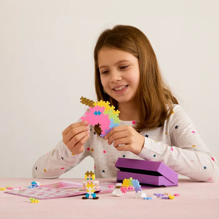 Girl building a colorful Plus-Plus unicorn and princess with an activity pad and purple storage case.