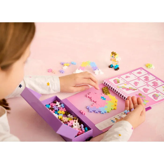Child building a colorful fairy design on a spiral activity pad using cross-shaped pieces from a purple tray.