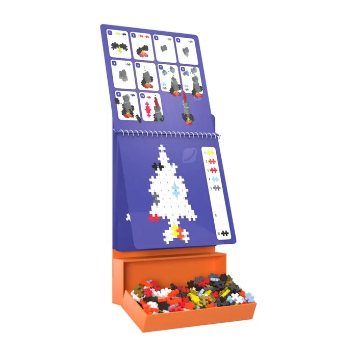 Purple spiral activity pad on an orange tray filled with colorful building pieces showing space rocket instructions.