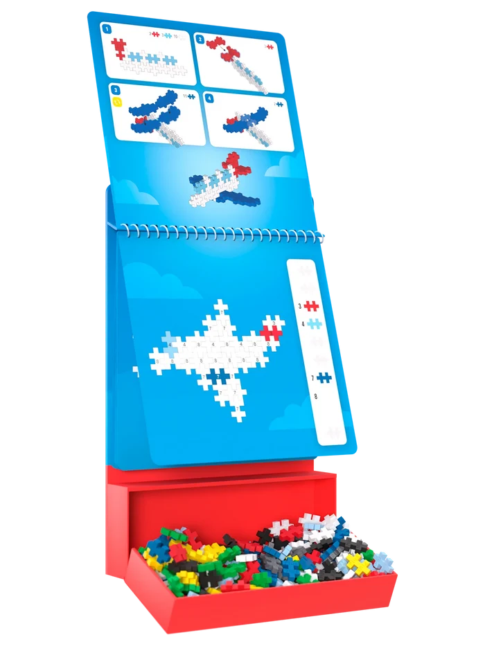Blue activity pad with airplane instructions and template, standing in a red tray filled with colorful Plus-Plus pieces.