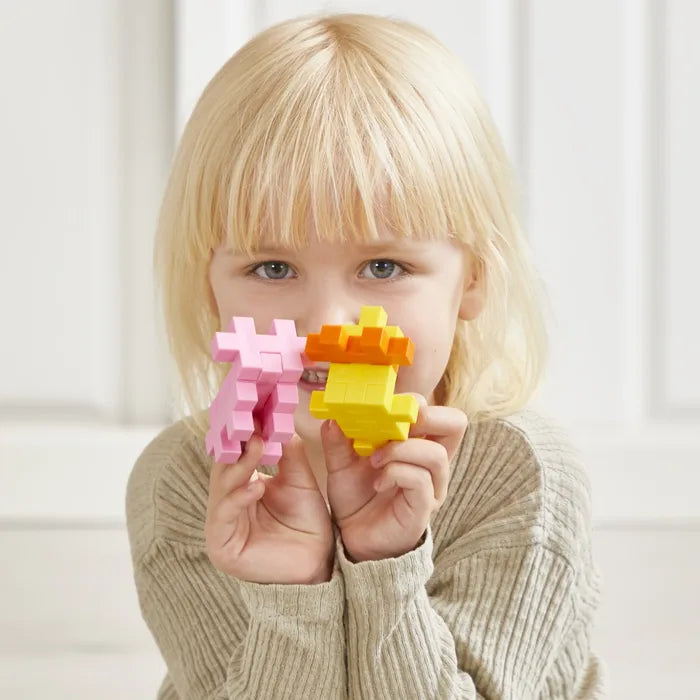 Young girl holds a pink and a yellow-orange animal figure built from chunky interlocking puzzle-shaped blocks.